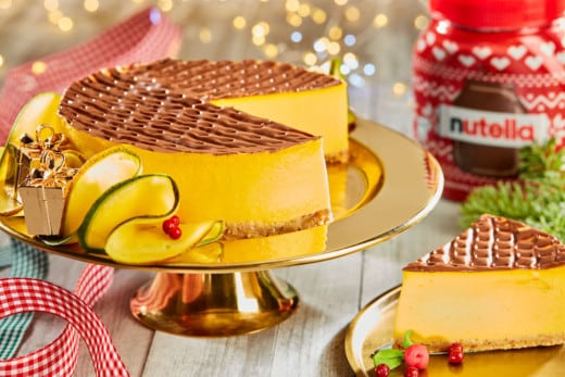 Cheesecake za studena a sklenice pomazánky Nutella na vánočně vyzdobeném stole.
