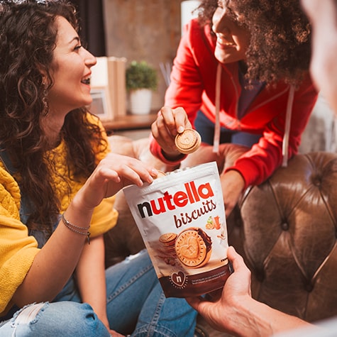 Freunde genießen Nutella‑Biscuits gemeinsam, Teller mit Keksen im Mittelpunkt.