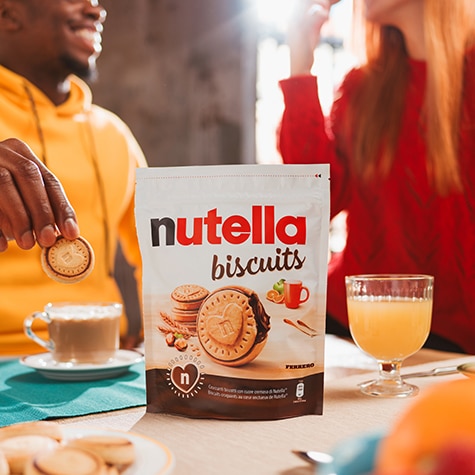 Packung Nutella‑Biscuits neben Frühstücksteller, serviert mit Kaffee und Saft.