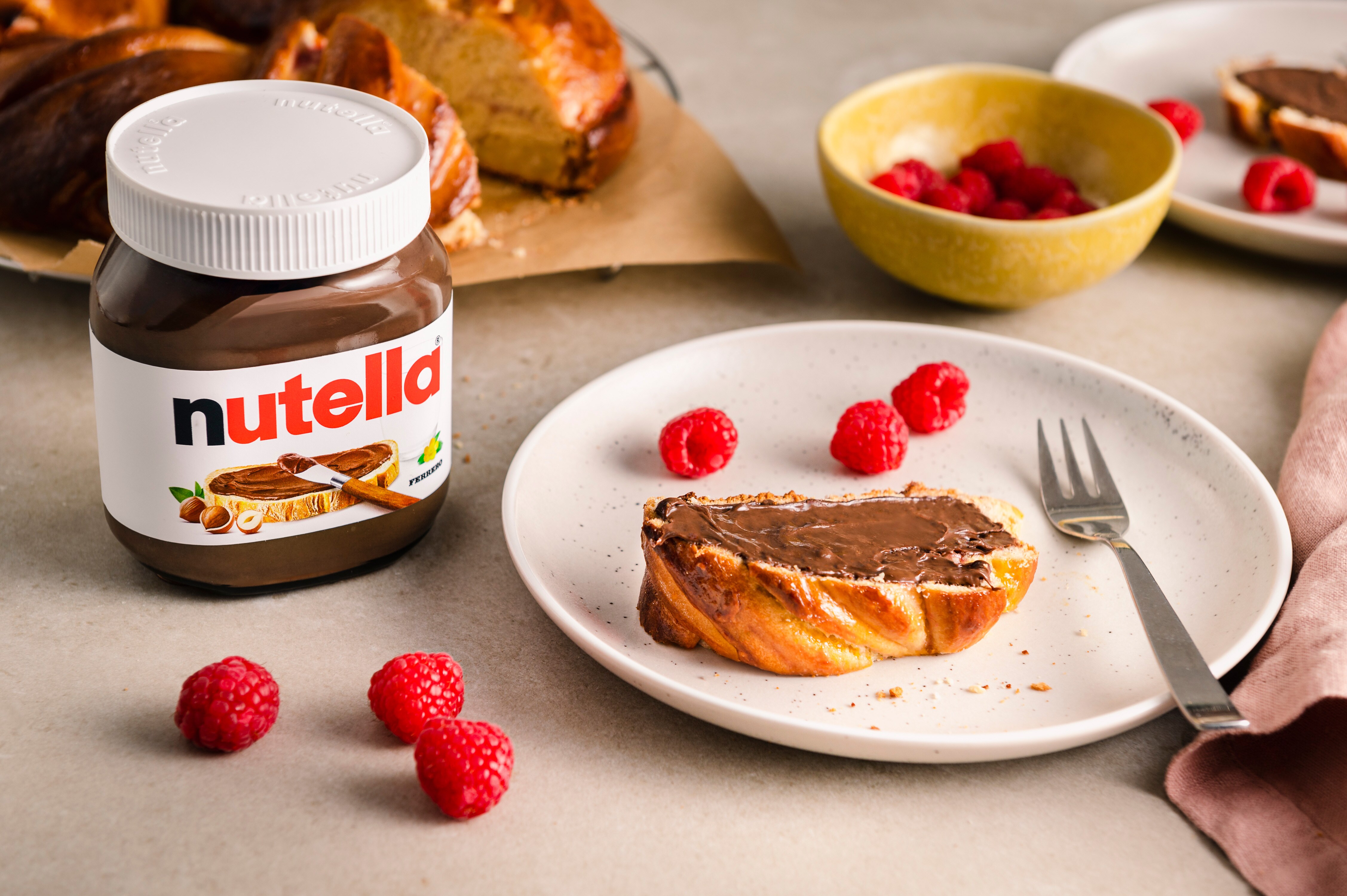 Scheibe Beeren-Babka-Hefezopf mit nutella® bestrichen, serviert auf einem Teller mit Himbeeren		