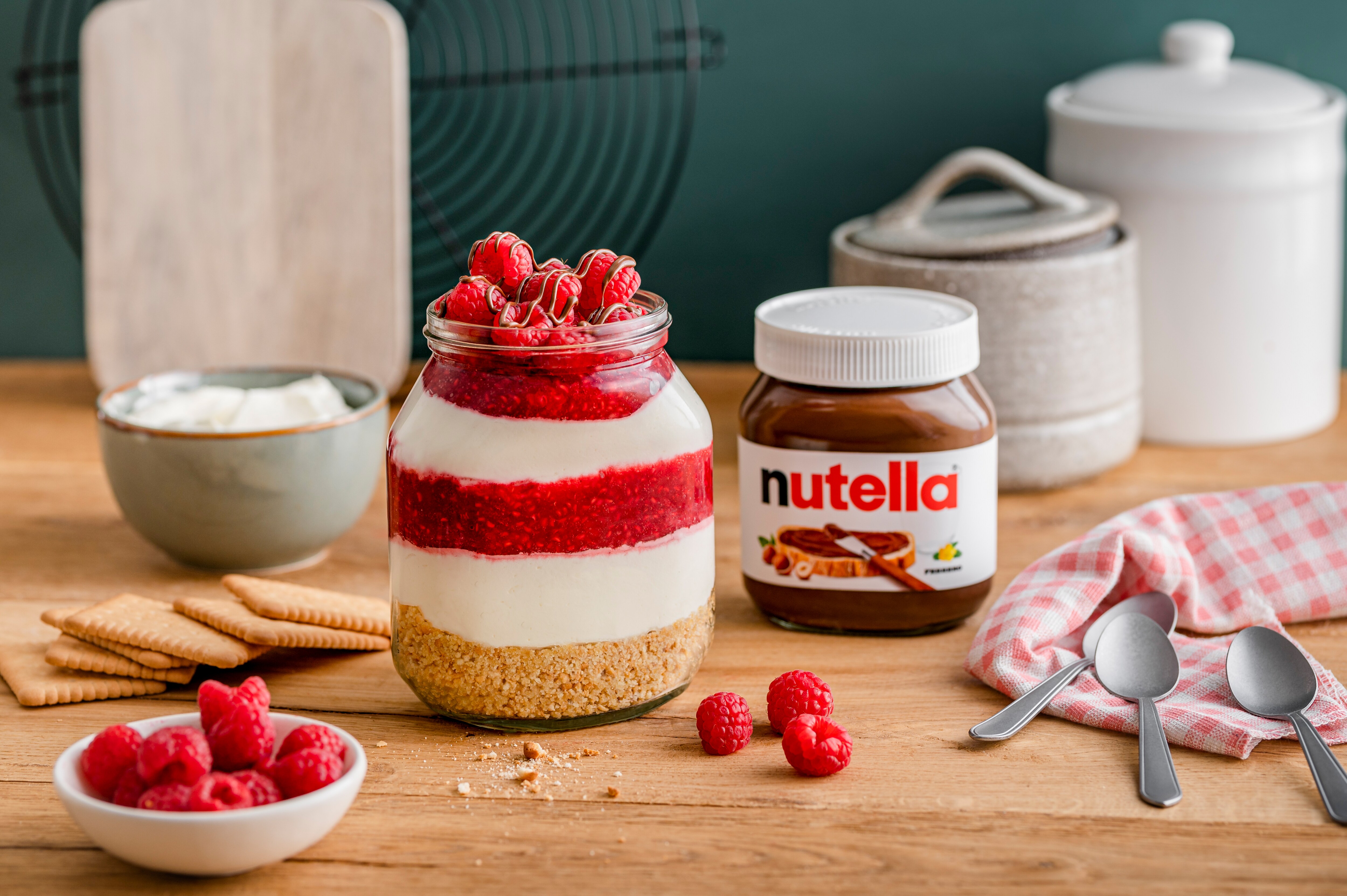 Himbeer-Käsekuchen im Glas mit nutella®, geschichtet mit Keksboden, Creme und Himbeerpüree, dekoriert mit frischen Himbeeren