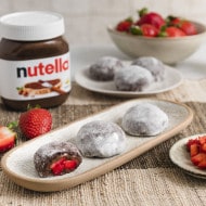 Nutella-Produktaufnahme: Glas auf rustikalem Brett mit Haselnussdekor und Löffel.