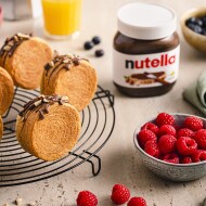 Servierte New York Rolls mit Nutella auf einem Gitter, begleitet von frischen Beeren und Nutella.