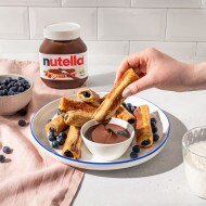 Herbstliches Nutella-Hero-Shot mit Nutella-Glas, Früchten und Gebäck.