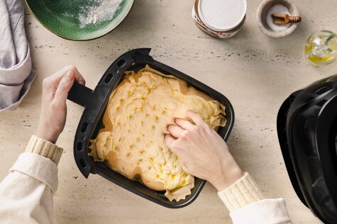Focaccia-Teig wird in einer Airfryer-Form vorbereitet und mit den Fingern eingedrückt, um die typische Struktur zu formen