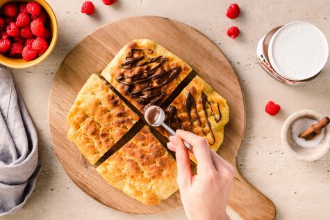 Airfryer-Focaccia in Stücken, warm serviert mit Nutella-Aufstrich und Holzlöffel.