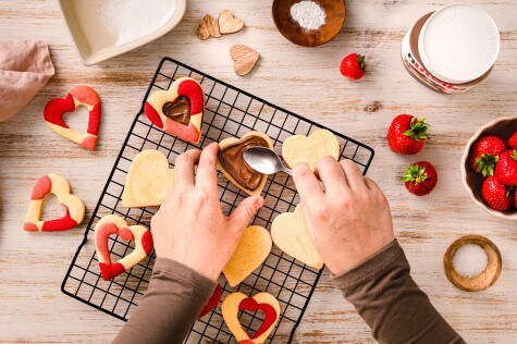 Nutella-Glas mit Croissant und Kaffee, urbanes Frühstücksstillleben auf Holztisch.