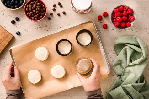 Croissant-Teigstücke werden in einer Backform vorbereitet, mit Beeren und Zutaten dekoriert.