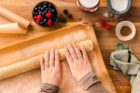 Nahaufnahme: Nutella-Glas mit glänzendem Aufstrich, Löffel und Haselnüssen.