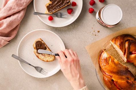 Nutella-Glas neben Waffeln, Ahornsirup und Beeren, serviert auf Teller.