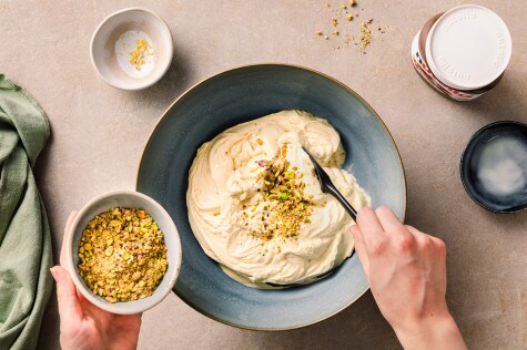 Pistazien werden in eine Schüssel mit aufgeschlagener Cheesecake-Creme gegeben, daneben nutella® und weitere Zutaten