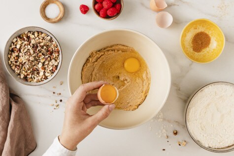 In einer großen Rührschüssel ist der Cookie-Teig bereits cremig verrührt und zwei Eigelbe liegen bereit, um untergehoben zu werden. 