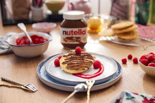 Fluffige Pfannkuchenwolken mit Nutella, gestapelt und leicht bestäubt.