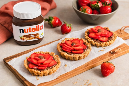 Bereinigtes Nutella Werbefoto: Glas mit Löffel und Haselnussgarnitur.
