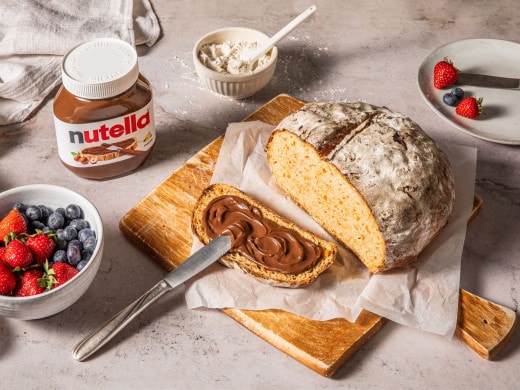 Frühstücksarrangement: Nutella-Glas mit Croissant, frischen Beeren und Haselnüssen.