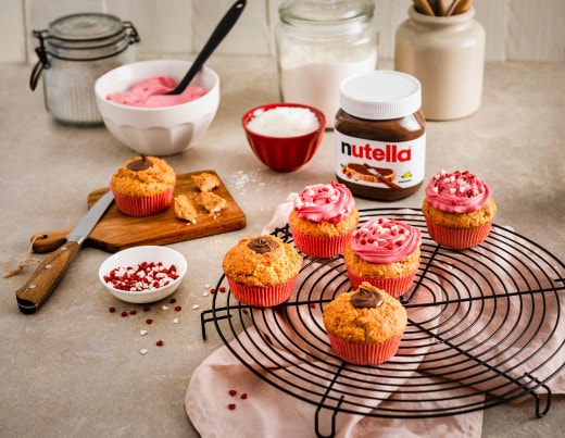 Valentinstags-Cupcakes mit Nutella-Frosting, Herzdekoration und rosa Zuckerglasur serviert.