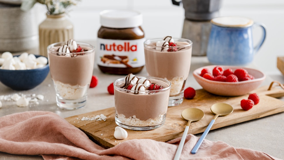 Leichte Nutella-Mousse in Gläsern, dekoriert mit Kakaopulver und Schokoraspeln.