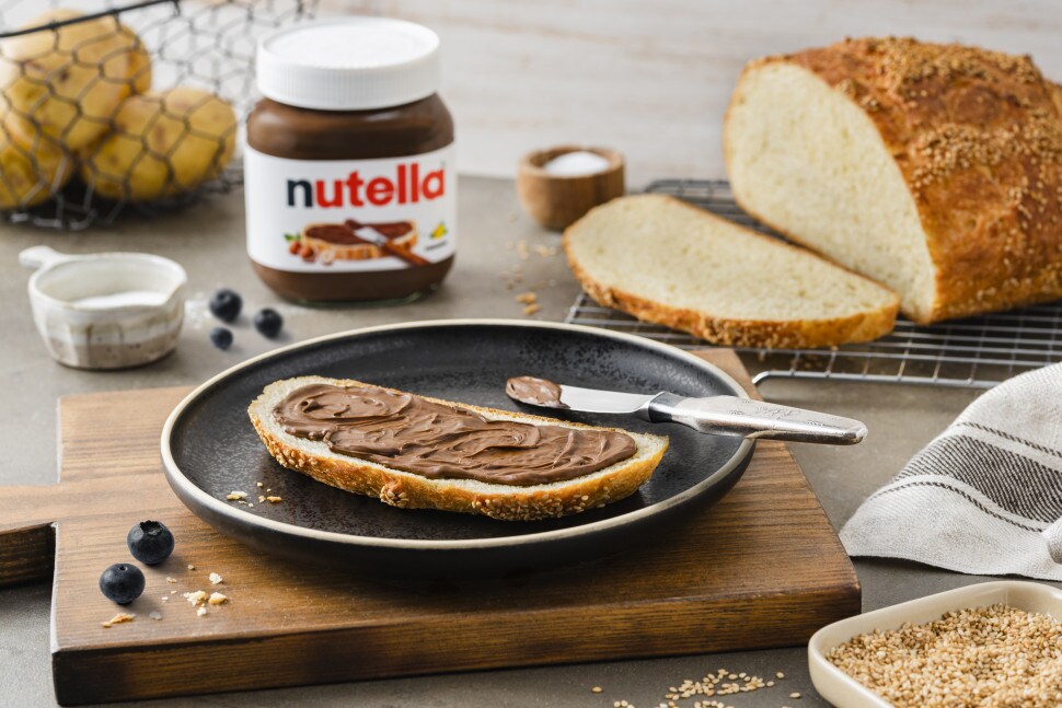 Verschiedene frisch gebackene Brote mit Nutella als Aufstrich serviert.