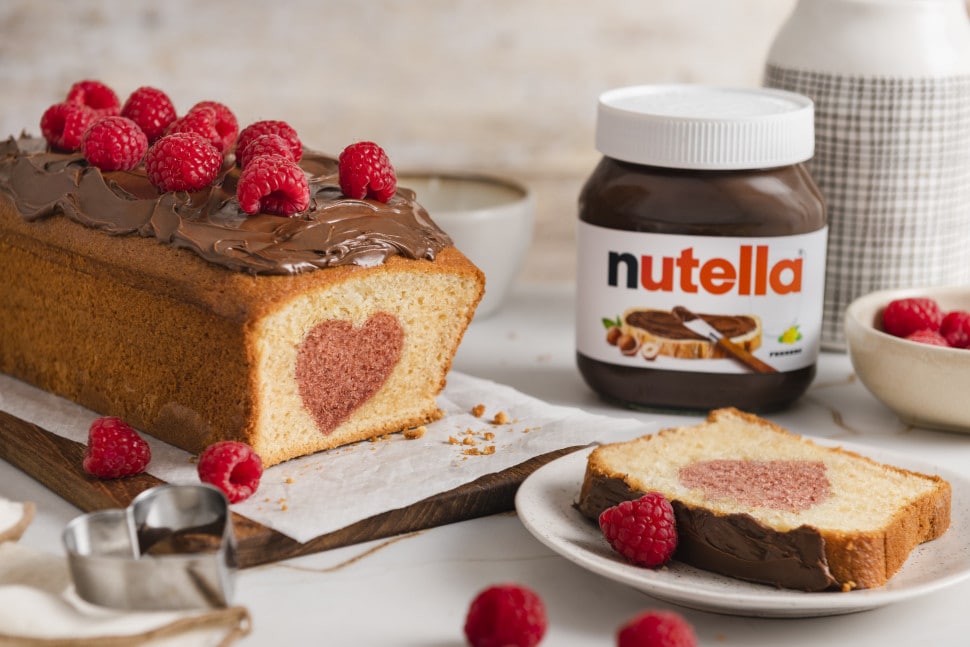 Nutella Glas dekorativ präsentiert mit Croissant und Beeren auf Holzbrett.