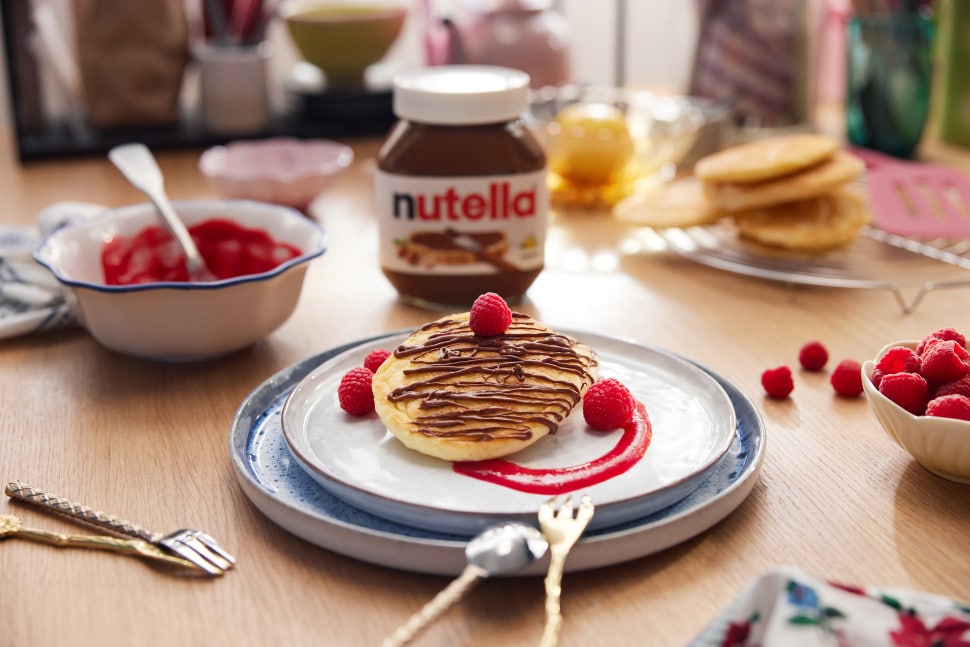 Fluffige Pfannkuchenwolken mit Nutella, gestapelt und leicht bestäubt.