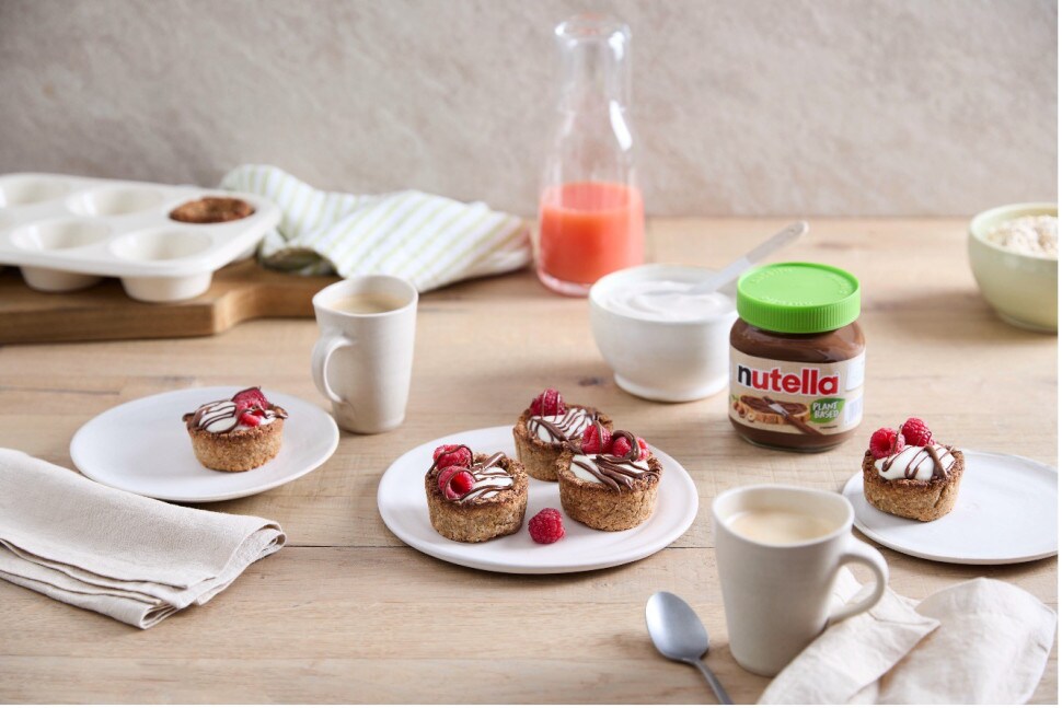 Granola-Cups mit Nutella Plant-Based, Beerenfüllung und Joghurt-Topping, serviert.