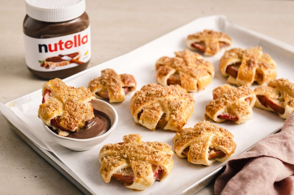 Gebackene Apfelringe mit Blätterteig auf Backblech, serviert mit nutella® als Dip		