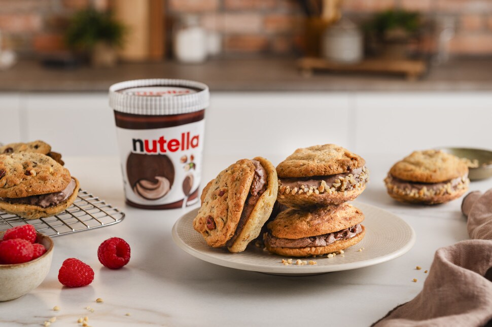 Mehrere Cookie-nutella-Eis-Sandwiches sind auf einem Bild drapiert. Die Sandwiches bestehen aus goldbraun gebackenen Cookies.