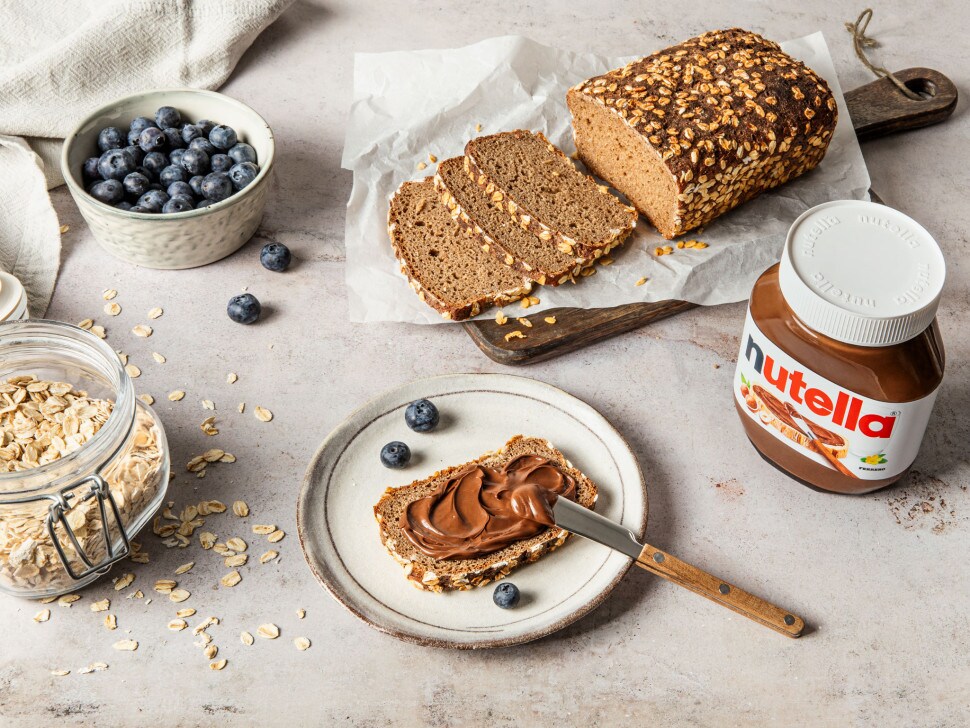 Gedecktes Frühstück: Nutella, Kaffee und frisches Gebäck stilvoll angerichtet.