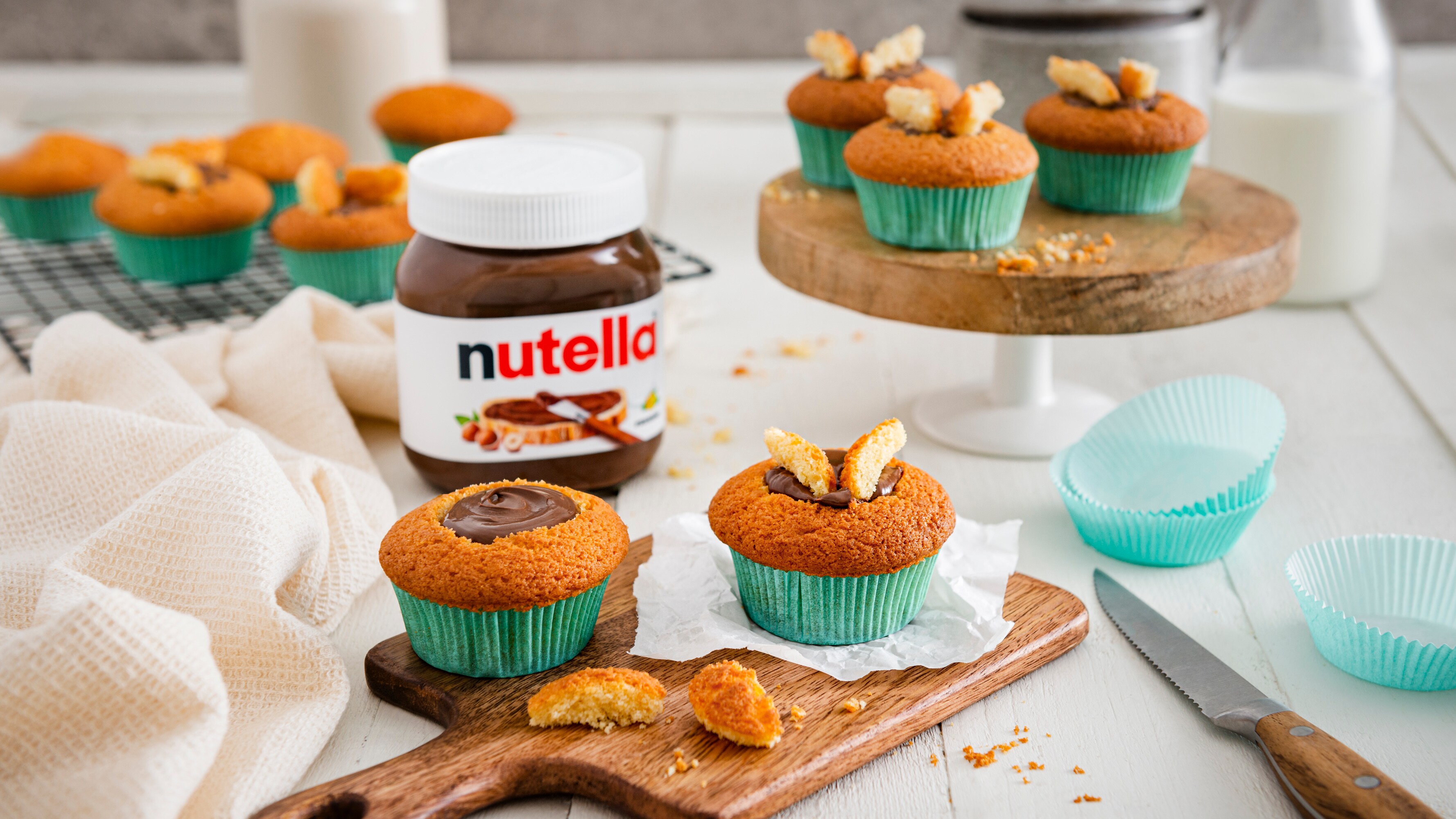 Zarte Vanille-Cupcakes mit Nutella-Frosting, Schokoladenstückchen und Nusskrokant auf Teller.