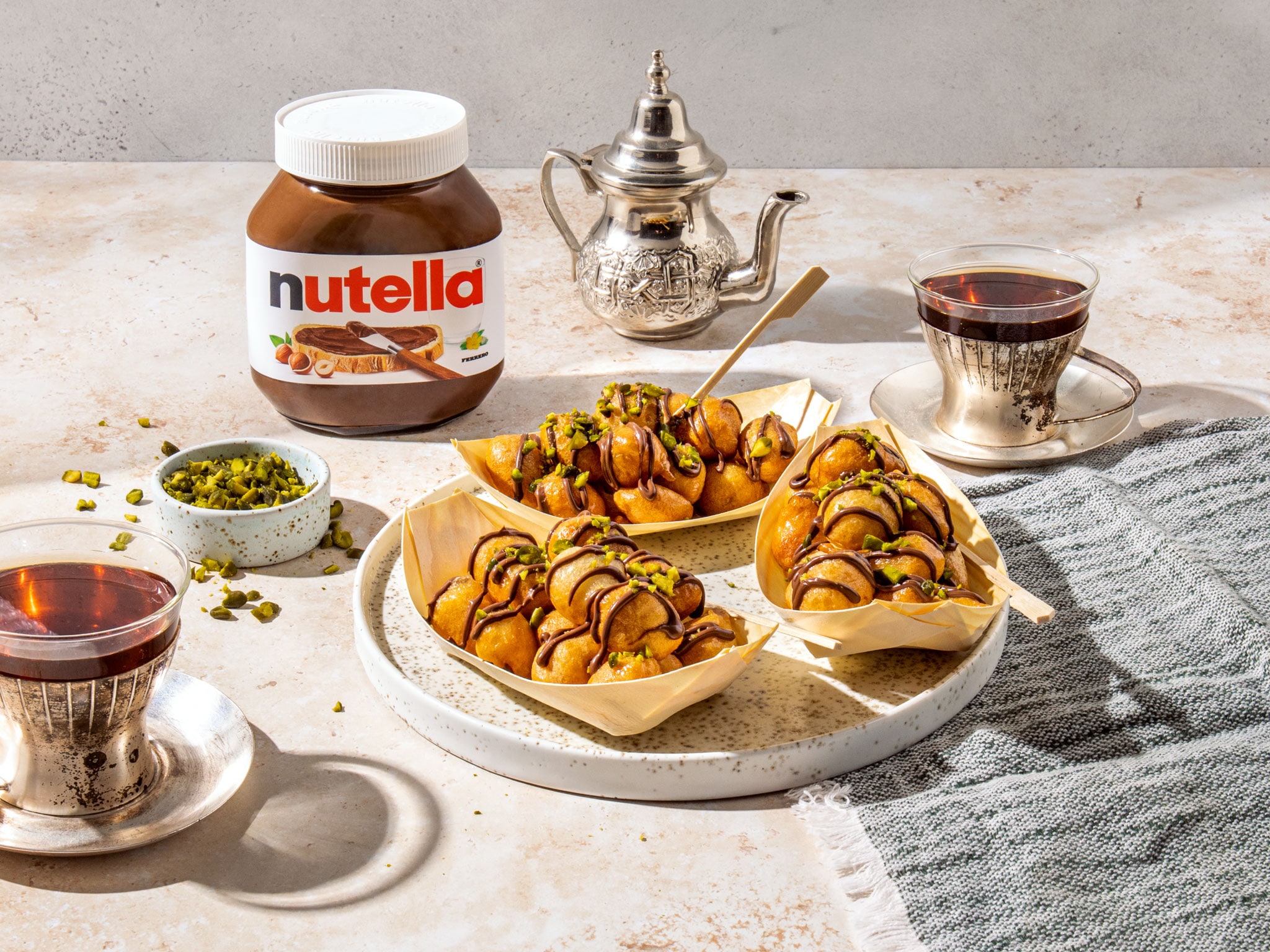Lokma-Teigbällchen glasiert, serviert warm mit Nutella-Dip auf Teller.