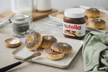 Stadt-Lifestyle: Nutella-Glas neben Croissant auf Café-Tisch, urbanes Frühstücksbild.