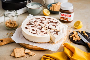 No-Bake Cheesecake mit Nutella-Füllung und Keksboden, garniert mit frischen Beeren.