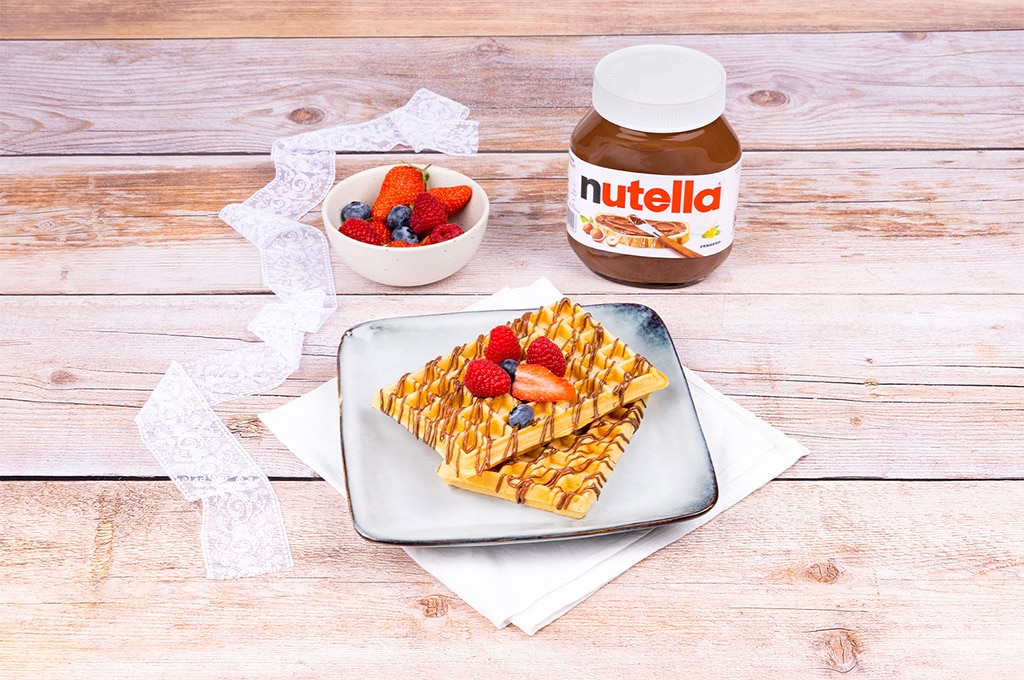 Gaufres dorées nappées de Nutella et fruits rouges frais, présentées.
