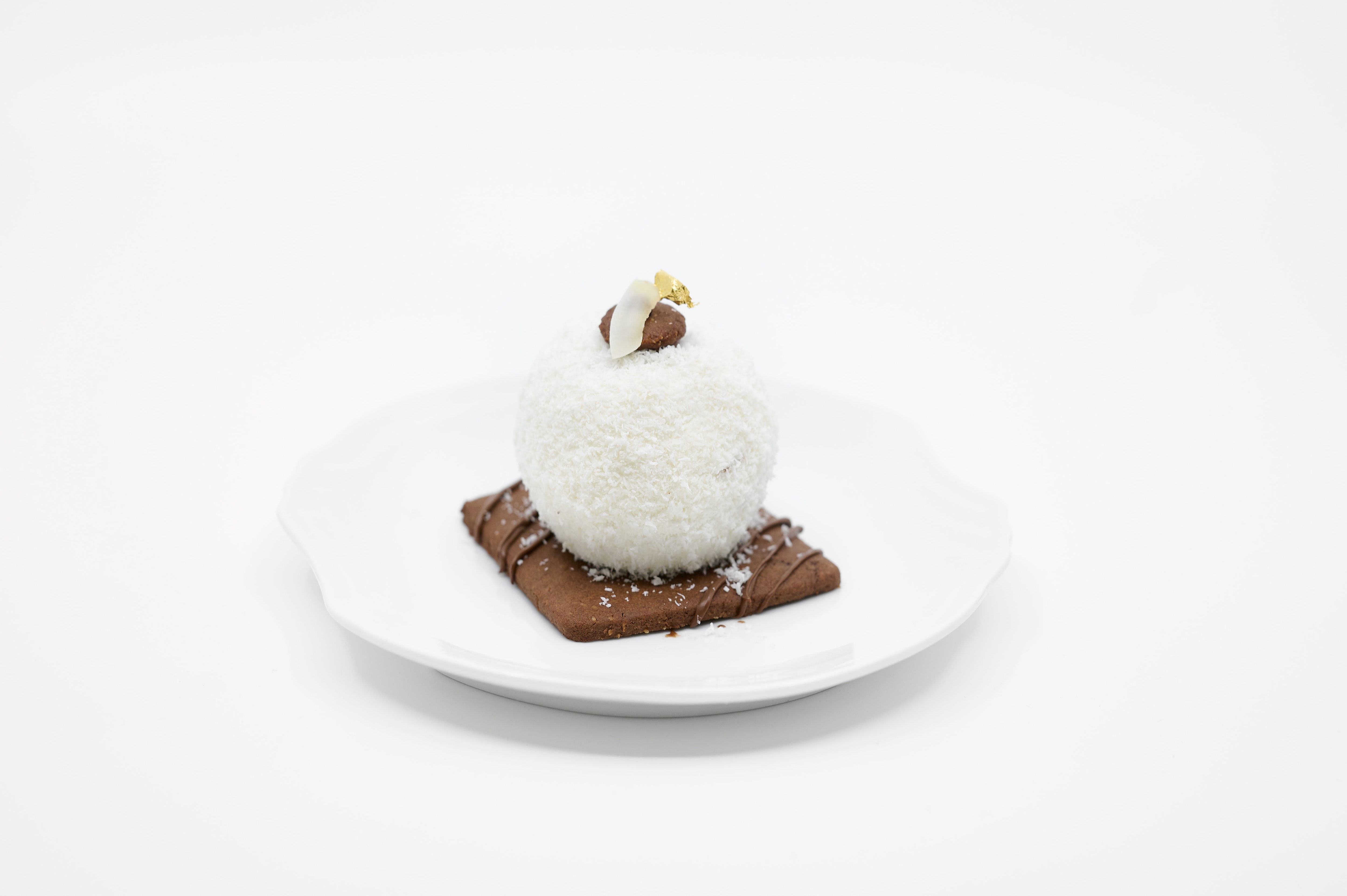 Boule coco-tonka fourrée au Nutella, glaçage brillant et décors exotiques.