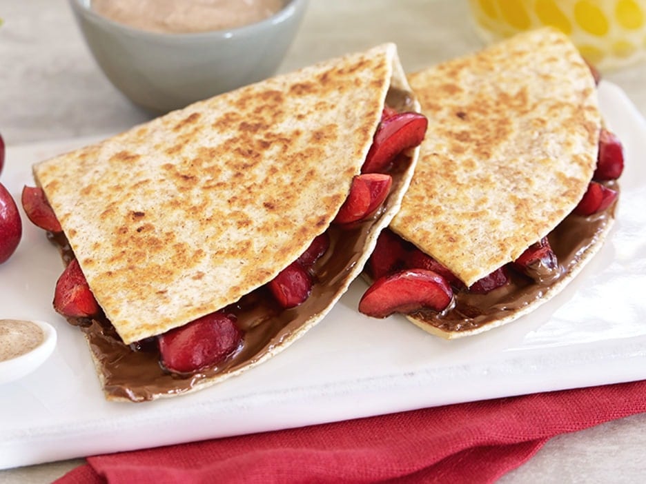Folded quesadilla stuffed with Nutella and cherry compote, sliced.