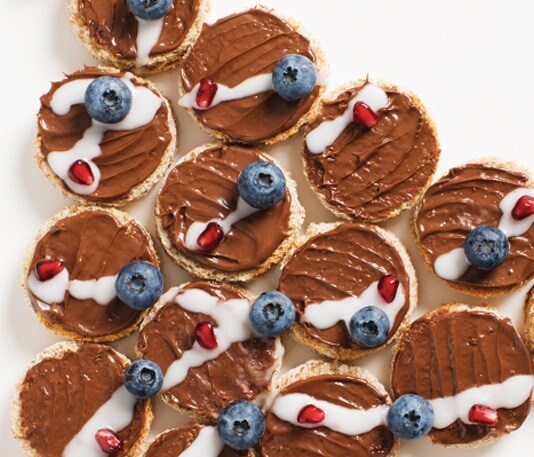 Christmas-tree-shaped toast spread with Nutella and decorated with berries.