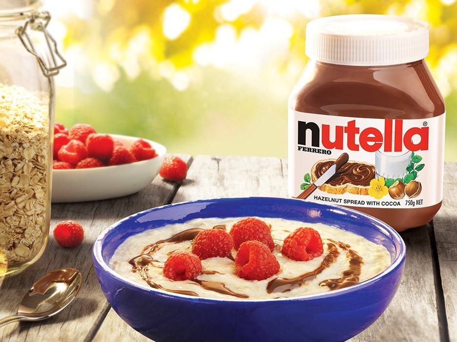 Bowl of oats topped with Nutella swirl and fresh raspberries.