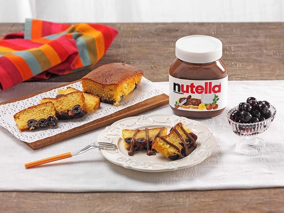 Sliced Nutella plum cake garnished with amarena cherries and powdered sugar.