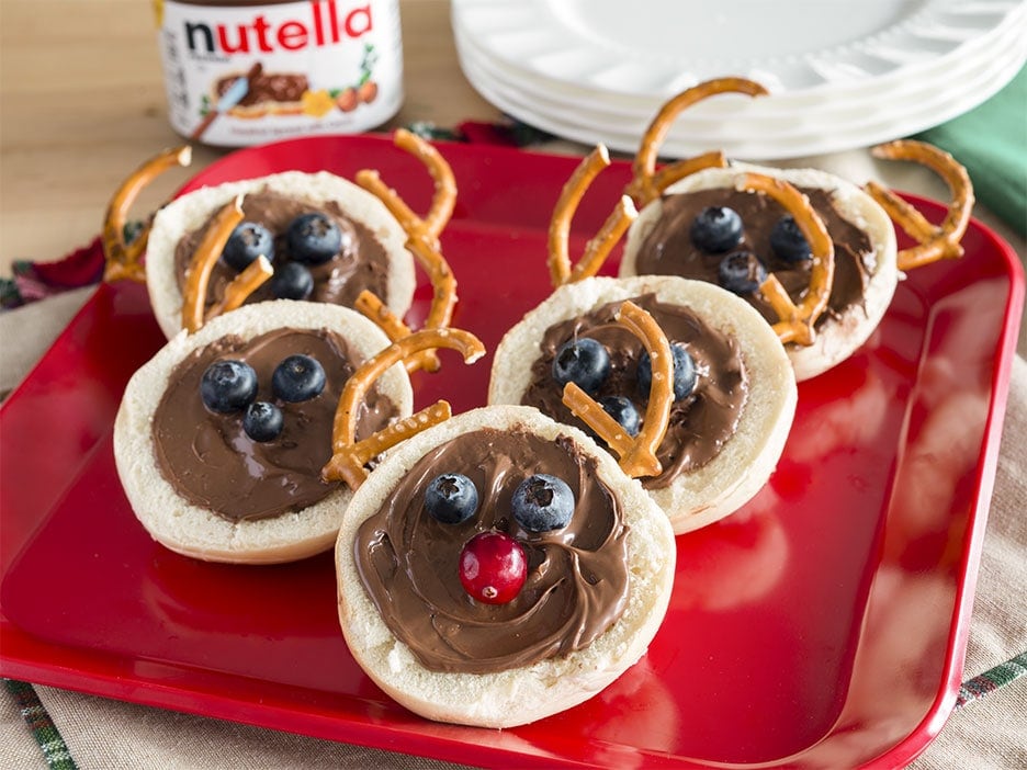 Reindeer-shaped bagels topped with Nutella and festive candy decorations.