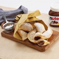 Golden Nutella-filled pastry pockets served warm on a white plate.