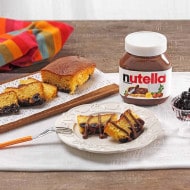 Sliced Nutella plum cake garnished with amarena cherries and powdered sugar.