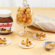 Small struffoli balls drizzled with Nutella and decorated with colorful sprinkles.