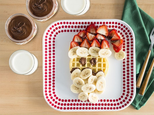Santa-shaped waffle decorated with Nutella and festive holiday toppings.