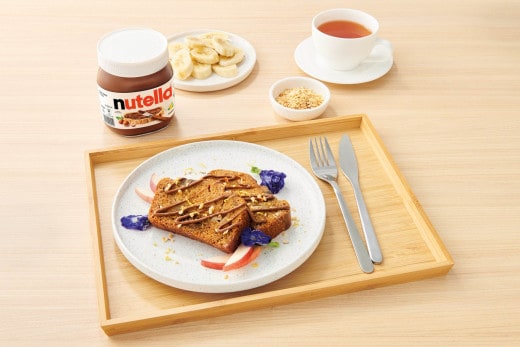 Banana bread loaf swirled with Nutella on a rustic wooden board.