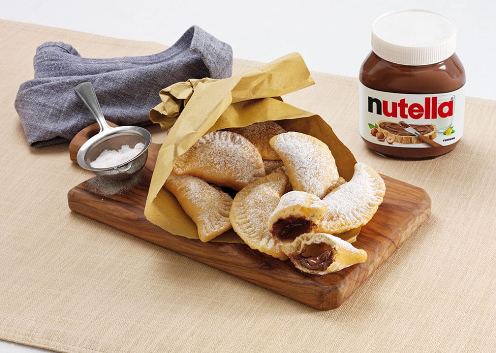 Golden fagottini puff pastry parcels filled with Nutella, dusted with powdered sugar.