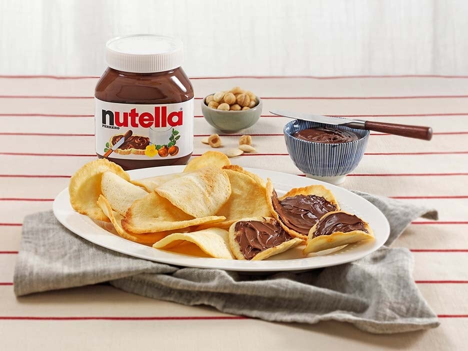 Thin almond tegole cookies layered with Nutella, stacked on parchment.