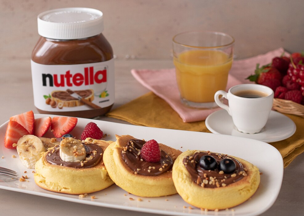 Pancake giapponesi alti serviti con Nutella e frutti di bosco.