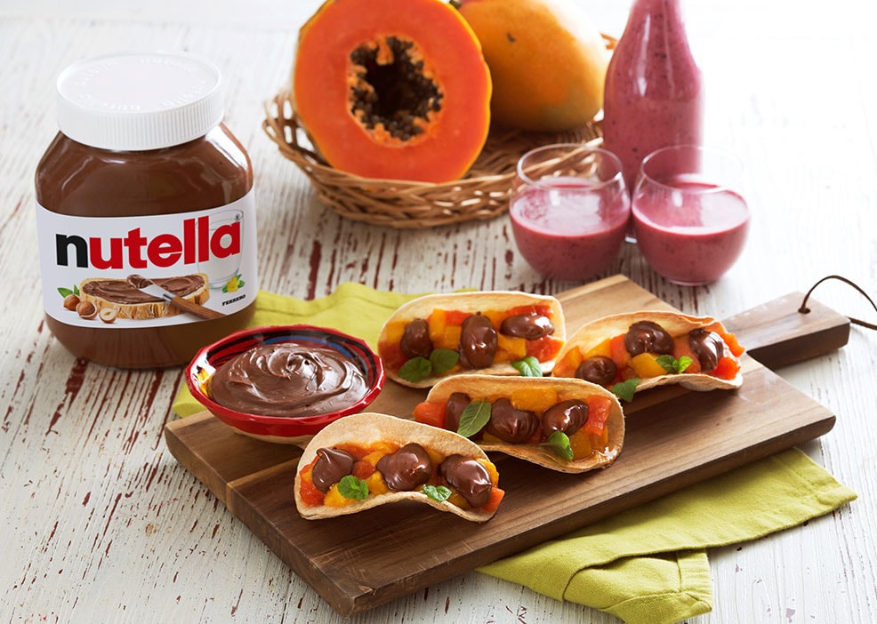 Tacos dolci ripieni di mango, papaya e Nutella, colorati.