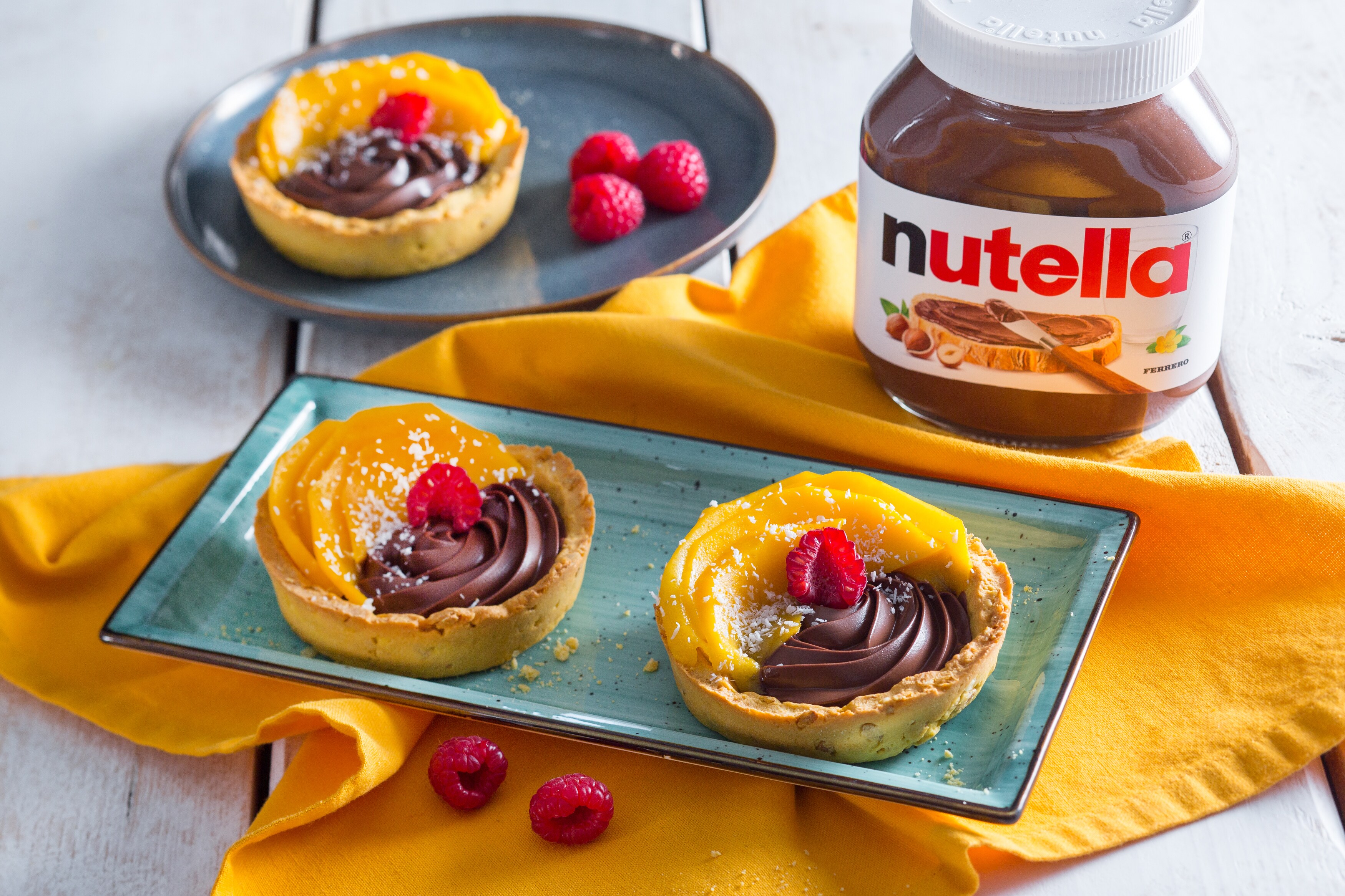 Crostatina mango e cocco con cuore di Nutella, guarnita.