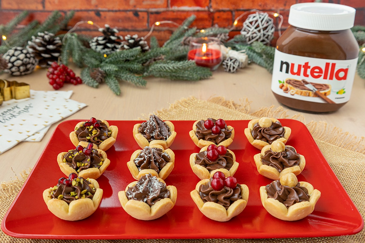 Tartellette con Nutella e crema, decorate con frutta e zucchero.